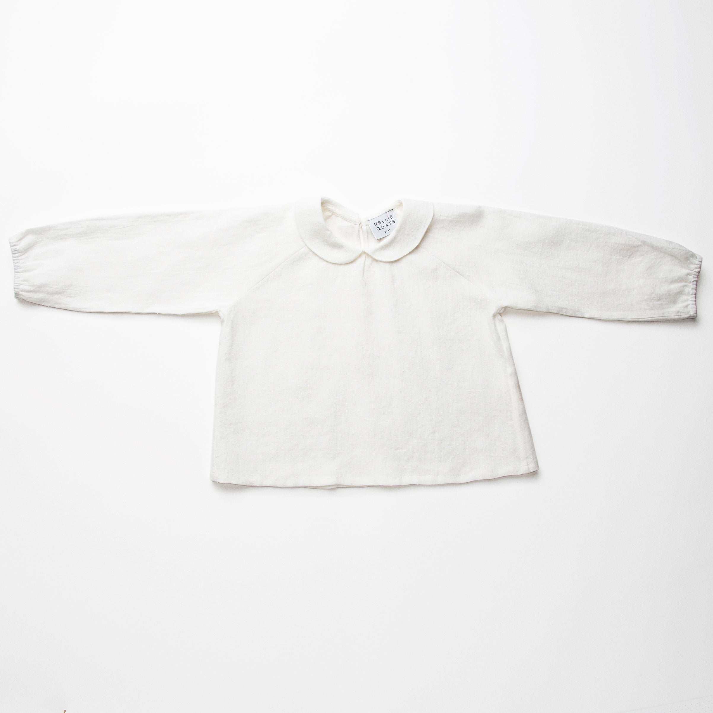 Loose fit, raglan sleeve white Linen blouse, with long elasticated sleeves, Peter Pan collar and single mother of pearl button at the back of the neck. 