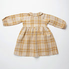 Long sleeve raglan dress with empire line, elasticated cuffs, Peter Pan collar and wooden button up front. Attached gathered skirt sits at a slightly longer length below the knee. Designed to be oversized for a stylish, comfortable fit. Made from a buttermilk plaid linen.