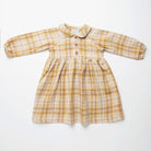 Long sleeve raglan dress with empire line, elasticated cuffs, Peter Pan collar and wooden button up front. Attached gathered skirt sits at a slightly longer length below the knee. Designed to be oversized for a stylish, comfortable fit. Made from a buttermilk plaid linen.