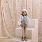 All in one romper, with bib front, elasticated waist and full bloomers with elasticated leg holes and poppers. Straps tie through loops at the back so fully adjustable (18-24M / 3-4Y). Smaller sizes fasten through a single button on the back, with buttonholes to adjust strap length (3-6M /6-12M /12-18M). Designed to sit at the top of the thigh, perfect paired with tights in winter and without in the summer. Made from Emery Walker Liberty print tana lawn cotton.