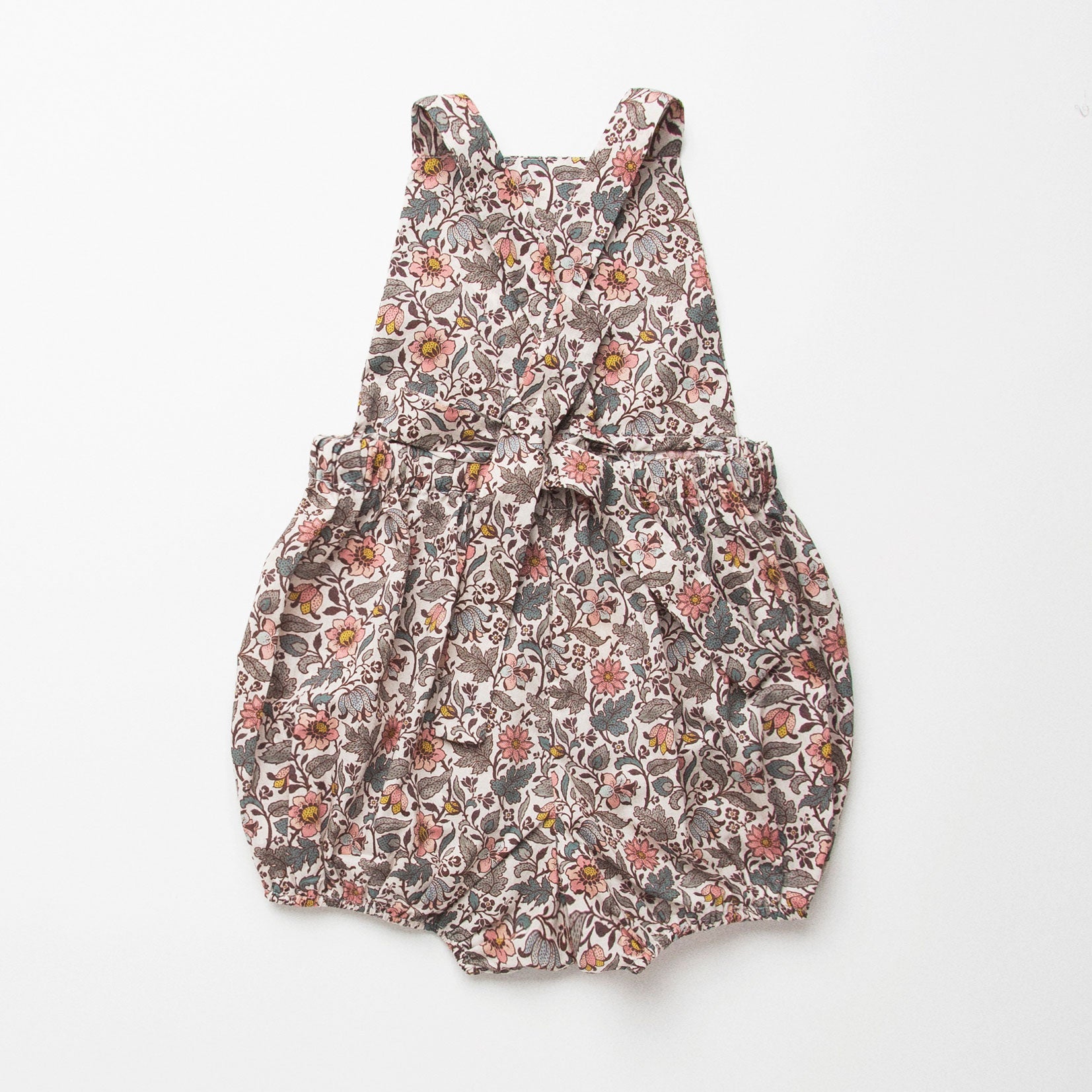 All in one romper, with bib front, elasticated waist and full bloomers with elasticated leg holes and poppers. Straps tie through loops at the back so fully adjustable (18-24M / 3-4Y). Smaller sizes fasten through a single button on the back, with buttonholes to adjust strap length (3-6M /6-12M /12-18M). Designed to sit at the top of the thigh, perfect paired with tights in winter and without in the summer. Made from Emery Walker Liberty print tana lawn cotton.