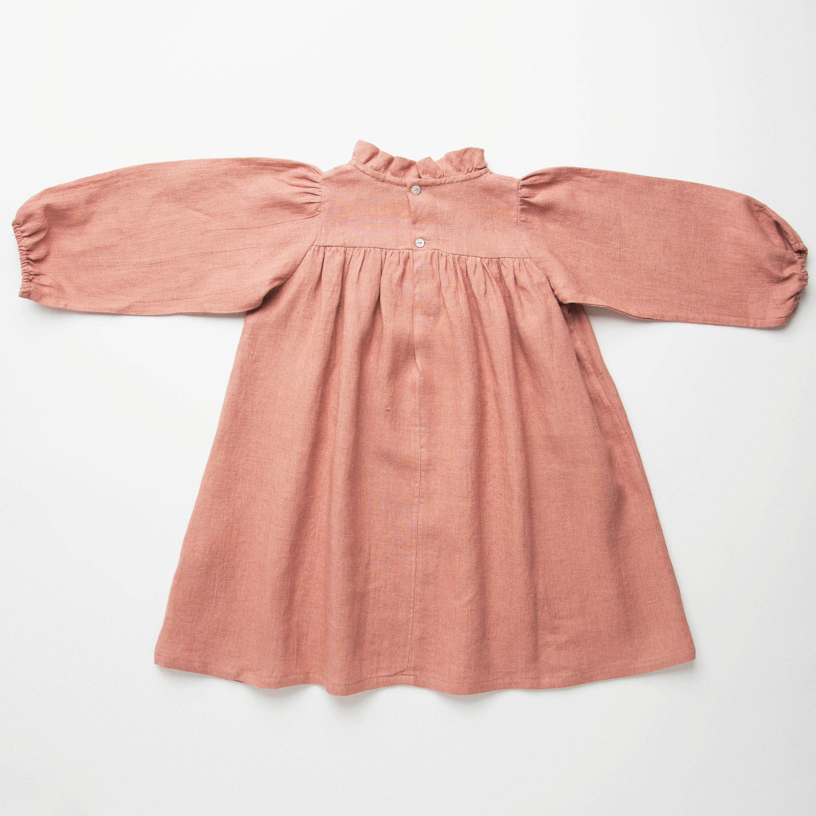 Full, floaty dress, with high empire line, full elasticated sleeves, small neck ruffle and mother of pearl buttons down the back yolk. Attached gathered skirt sits at a longer length below the knee. Designed to be oversized for a stylish, comfortable fit. Made from beautifully soft, dusty rose linen.