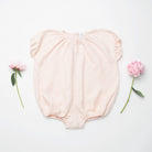 All in one romper, with short puffed elasticated sleeves and gathered neck to create a full, loose body shape. Closes at the back with single mother of pearl button, has elasticated leg holes and poppers for ease of opening. Designed to sit at the top of the thigh, perfect layered over tights in cooler weather and without in the summer. Made from super soft pale pink stripe linen.