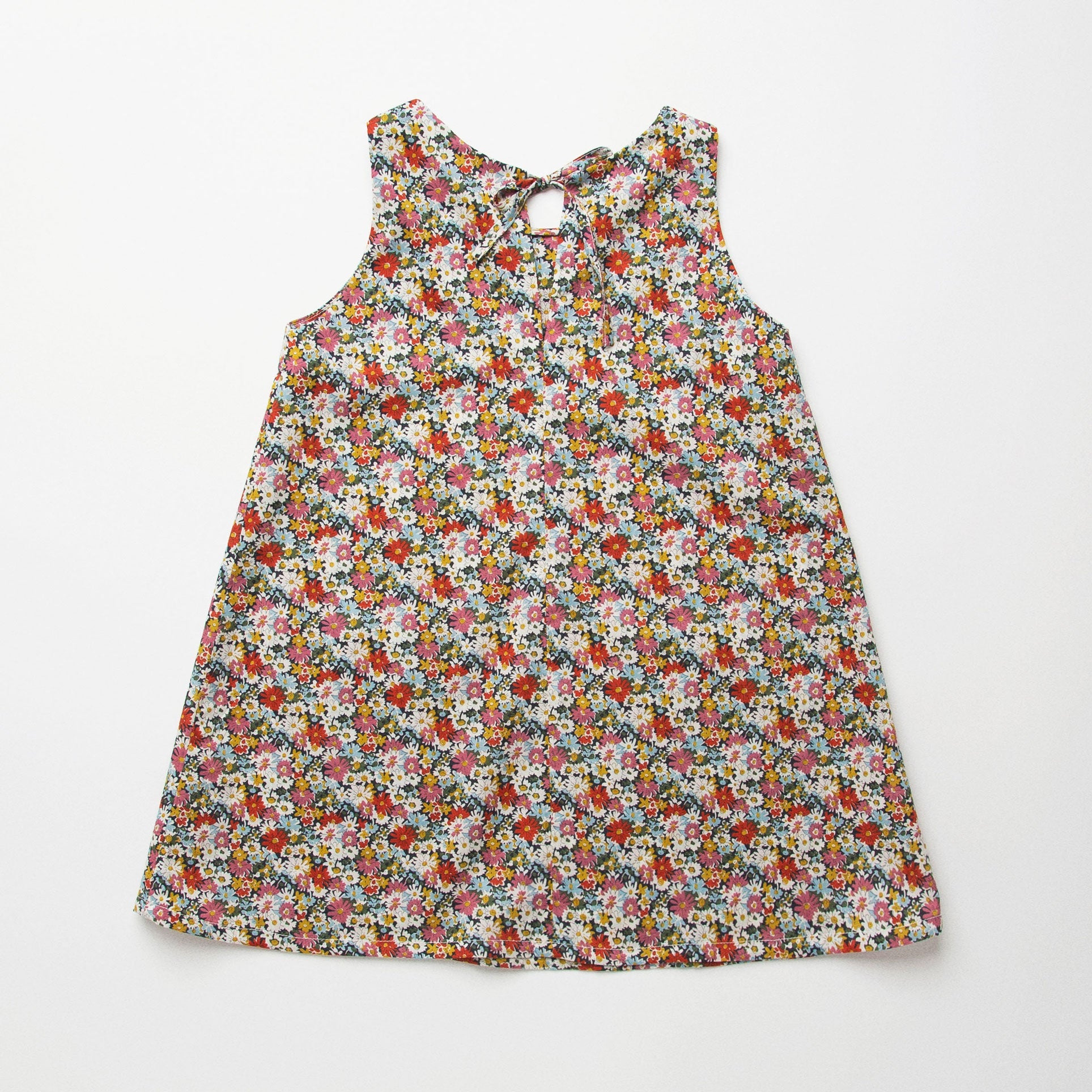 Simple A-line shaped pinafore dress with front pockets and tie at the back of the neck. Designed to sit above the knee and is perfect layered over an NQ blouse or stripped back in warmer weather. Made from beautiful Libby Liberty print tana lawn cotton.