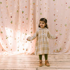 Long sleeve raglan dress with empire line, elasticated cuffs, Peter Pan collar and wooden button up front. Attached gathered skirt sits at a slightly longer length below the knee. Designed to be oversized for a stylish, comfortable fit. Made from a buttermilk plaid linen.